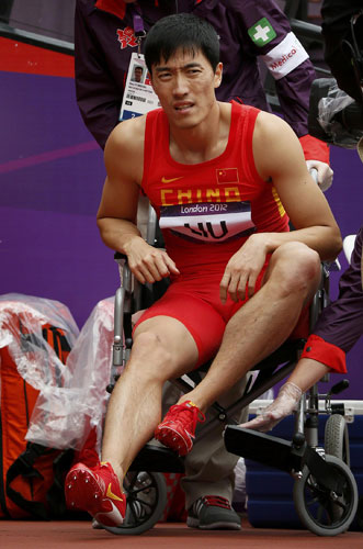 China's Liu Xiang is assisted onto a wheelchair after suffering an injury during his men's 110m hurdles round 1 heat during the London 2012 Olympic Games at the Olympic Stadium August 7, 2012. Liu hit by two-time injury-worry before London Olympics