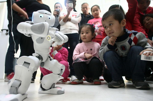 Children and their parents check out a robot practicing tai chi at the pediatric unit of Shandong University's Qilu Hospital in Jinan on Wednesday. Putting the robot in tai chi