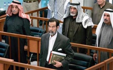 Taha Yassin Ramadan (L), Saddam Hussein (2nd L) holding a Koran, Abdullah Kazim Ruwayyid (2nd R), and Mizhar Abdullah Ruwayyid (R) stand at their trial held in Baghdad November 28, 2005.
