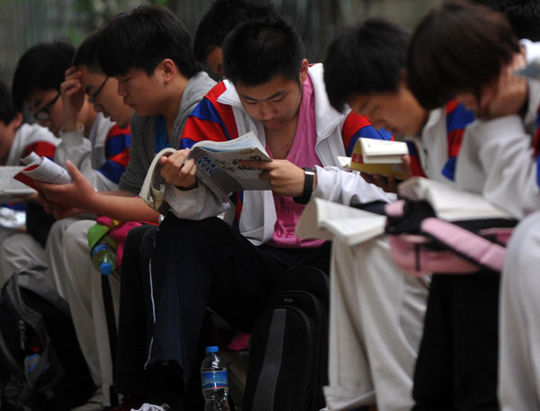 Students study while waiting outside a test site in Beijing, June 7, 2013. Big exam day kicks off