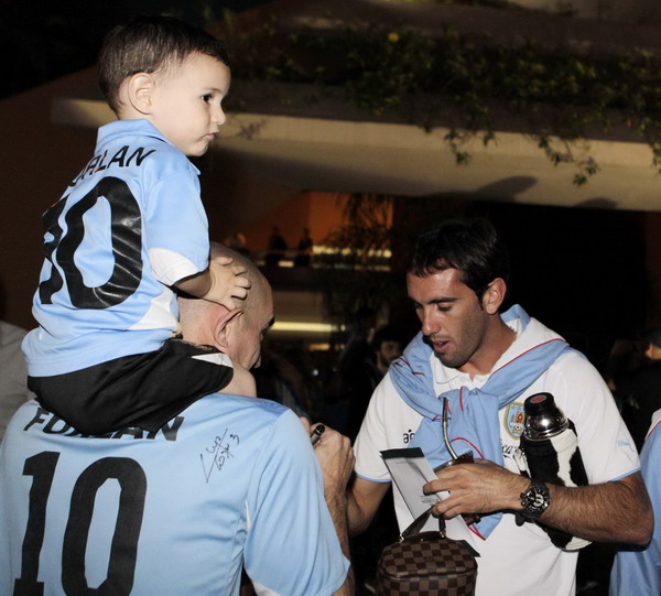 Uruguayan soccer player Diego Godin (R) signs autographs after arriving at the Silvio Pettirossi International Airport in Luque Oct 10, 2011. S America geared up for world cup qualifying match
