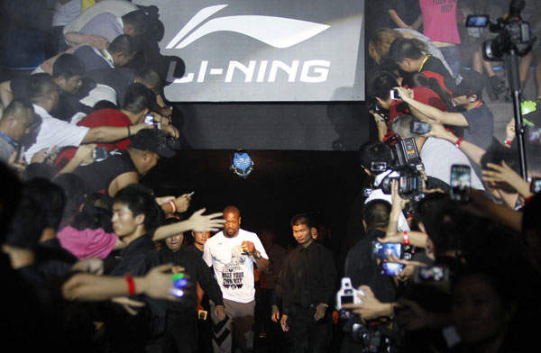 Fans gesture as NBA Miami Heat's Dwyane Wade (bottom, L) arrives at a promotional event for Li Ning's Way of Wade sneakers in Beijing, in this July 3, 2013 file photo. Sportswear maker ANTA persists with overseas push
