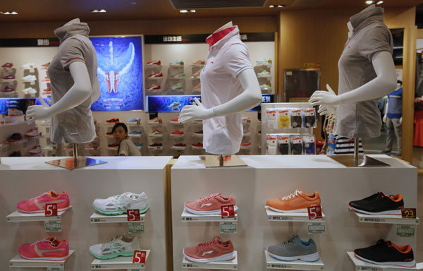A woman is seen behind shelves displaying Li Ning shoes and shirts at a store in Beijing, Aug 6, 2013. Li Ning stages comeback