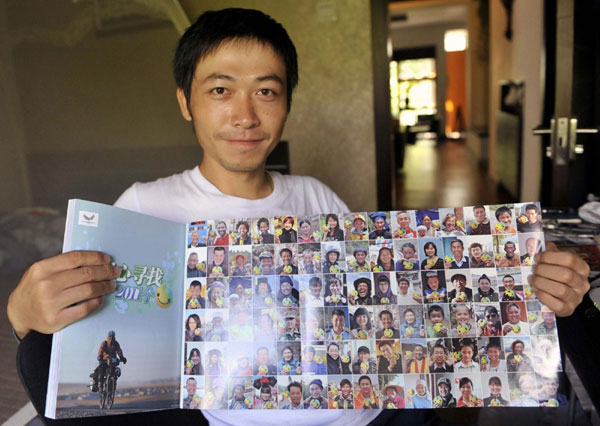 Zhou Ziqian shows photos of people posing with UU, the mascot for the Shenzhen Summer Universiade, in Shenzhen, Guangdong province, on August 14, 2011. Zhou, a Shenzhen resident and cycling enthusiast, spent 400 days biking around China, collecting 2,011 photos of people posing with UU and promoting the Universiade. Man's epic bike journey promotes Universiade