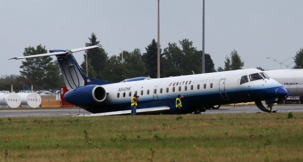 Workers take photographs of a United Express plane after it skidded off the runway at the Ottawa International Airport Sept 4, 2011. United Express plane skids off runway